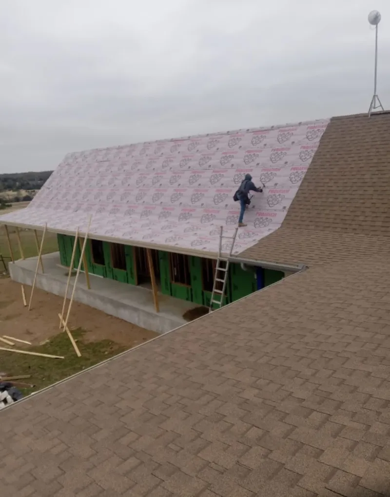 Worker preparing underlayment for a metal roof installation in Woodlawn